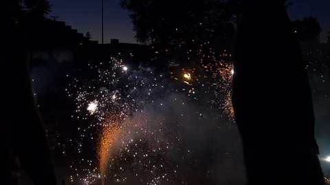 Silhouette holding firework in front of other fireworks in the dark slow motion 스톡 동영상 89169330