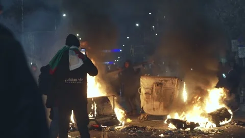 Silhouette of hooligans in front of burning containers at night in the city Stock Footage 324560575