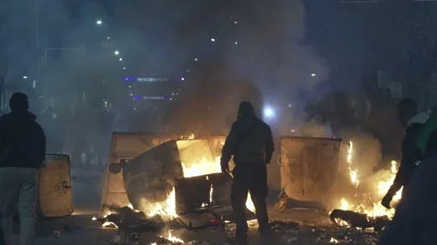 Silhouette of hooligans in front of burning containers at night in the city Stock Footage 324564174