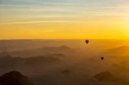 Silhouette Of Hot Air Balloons In The Golden Sky Over The Sand Dunes At Sunrise Stock Photos