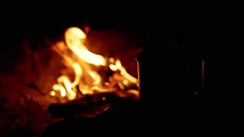 Silhouette of a Hot Cup of Coffee on a Blurred Background of a Campfire at Night Stock Footage 253588470