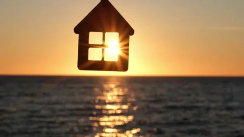 Silhouette of house shaped keychain on background of sea sunset in sun rays Stock-Footage 301372360