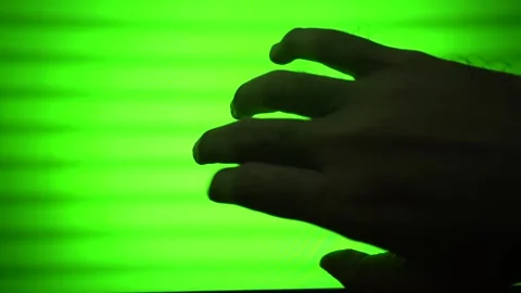 Silhouette of a human hand gesturing and reaching over a bright green scree.. Stock Footage 340490597