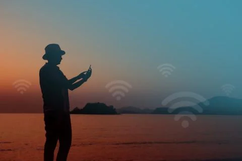 Silhouette of human using internet via smart phone at the Beach Stock Photos