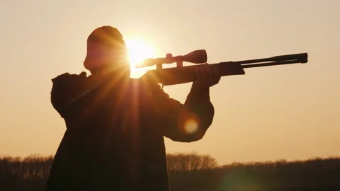Silhouette of the hunter takes aim at the optical sight at sunset Stock Footage 143313743
