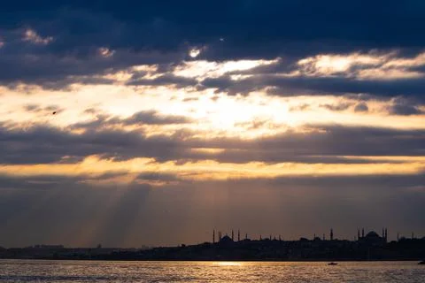 Silhouette of Istanbul at sunset with dramatic cloudy sky and sunlight beams. Stock Photos