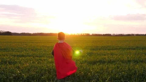 The silhouette of a kid running through a green meadow during sunset. A Stock Footage 242598739