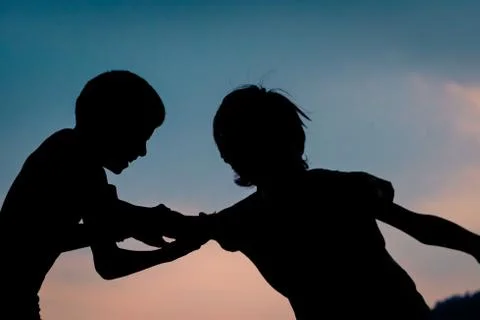 Silhouette of kids playing or fighting Stock Photos