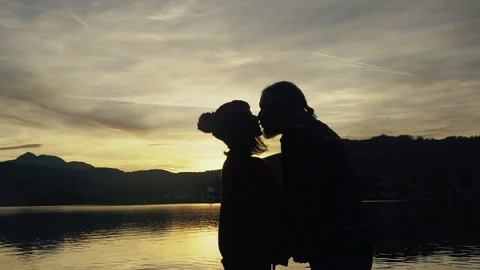 Silhouette of kissing couple against sunset at mountain top. Romantic scene of Stock Footage