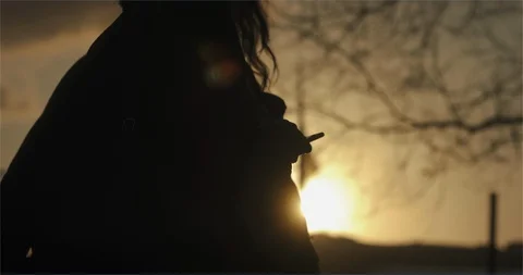 Silhouette of lady using iPhone at sunset Stock Footage 99808801