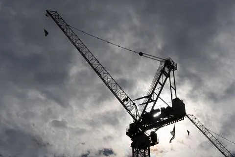 Silhouette of a large construction crane with clouds in the backgroud. Stock Photos