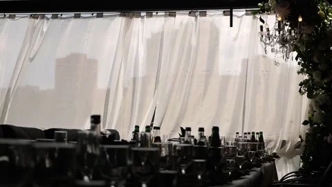 The silhouette of a large gazebo with set tables and fluttering curtains. Stock Footage 334120037