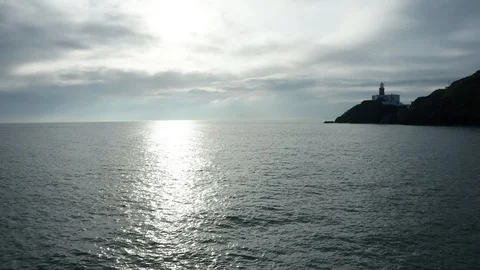 Silhouette of a lighthouse, in a strong backlight at the ocean, aerial Vidéo 119773106