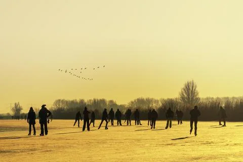 Silhouette of local Dutch skating on the Kinderdijk frozen canal water with Stock-Fotos