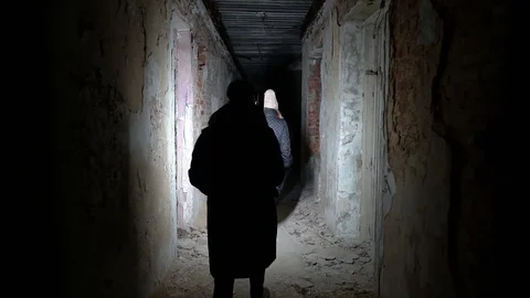 Silhouette of lone man walking through dark abandoned building corridor Stock Footage 124386867