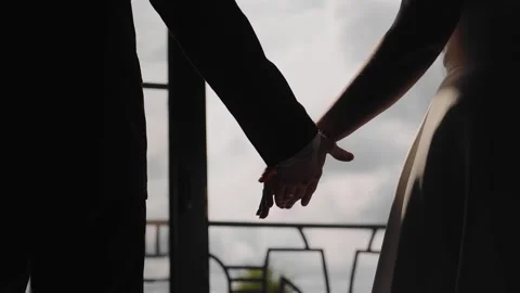 The silhouette of the lovers' hands against the background of light Stock Footage 250483970