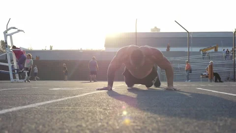 The silhouette of a male bodybuilder doing push-ups on a public sports field. Stock Footage 295842201