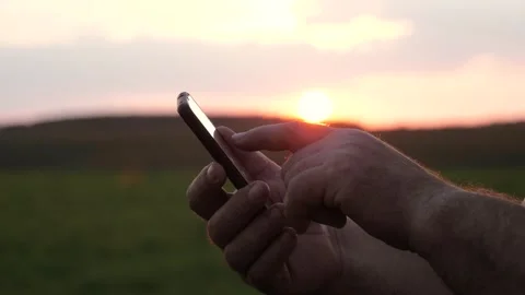 Silhouette of male hands using a smartphone at sunset Stock Footage 334340407