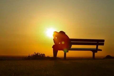 Silhouette male sitting on a bench at sunset Stock Photos