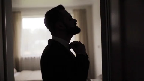Silhouette of man adjusting bowtie looking at mirror preparing for date or event Stock Footage 87009786