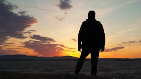 The silhouette of a man admires the cloudy sky at sunset. Stock-Footage 337563267