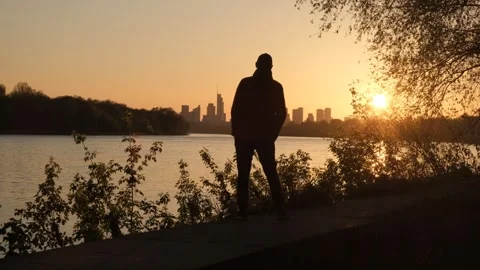 The silhouette of a man, against the backdrop of a river and a remote city. A Video stock 240318697