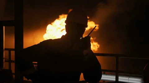 Silhouette of a man against a flame. A man in helmet on a background of fire Stock Footage
