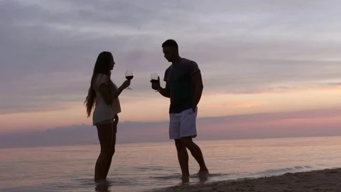 Silhouette of a man and a female on the beach they drink wine from glasses Stock-Footage 77166312