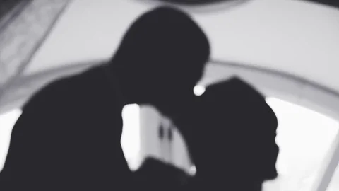 Silhouette of a man and a woman against a light window, a wedding in black and Stock Footage