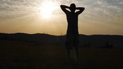 Silhouette of a Man in the Background of the Sun Keeps His Hands Behind His Stock Footage 67343610