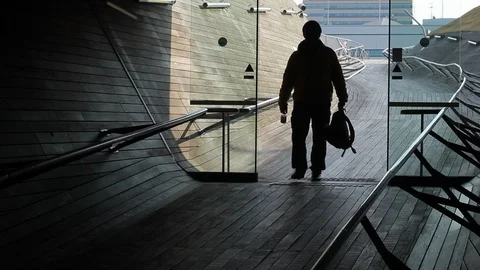 The silhouette of a man with a backpack in his hands enters through the Stock Footage 105059685