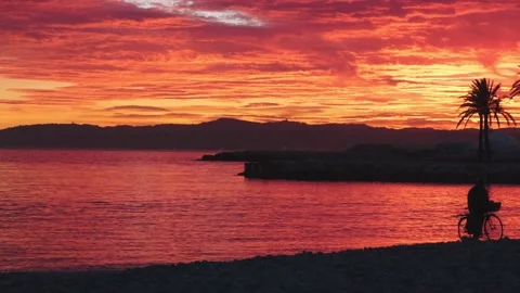 Silhouette of the man with a bicycle walking on a dramatic sunset. Stock Footage 229943867