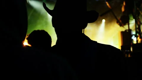 Silhouette of man with cowboy hat at a music festival in front of stage Stock Footage