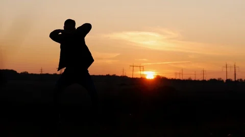 Silhouette of a man crazy dancing in a field at sunset Stock Footage 118431190