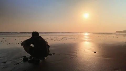 Silhouette of Man Crouching on Beach Sand at Sunset Ocean View Stock Footage 345462421