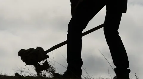 Silhouette of man digging a hole with a shovel slow motion close up Stock Footage