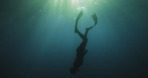 Silhouette of man diving down and snorkeling in long fins in tropical water Stock Footage 259919662