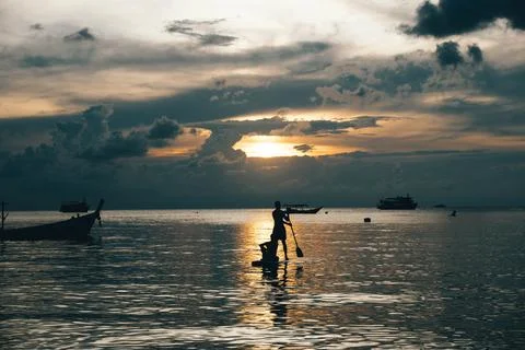 Silhouette of a man doing paddle, with a dramatic sunset sky and cloud, in .. Stock Photos