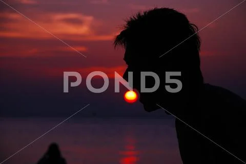 Silhouette Of Man Eat Sun In Evening On Beach Sea Blue Sky