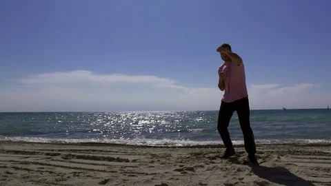 The silhouette of a man engaged in battle with the shadow on the beach in the Vidéo 107656446