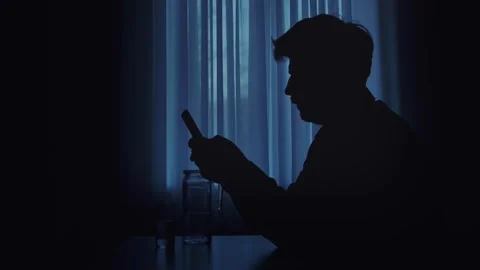 Silhouette of a Man Engaged with Smartphone in Dim Light Stock Footage 305188541
