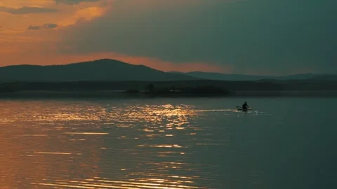 Silhouette of a man floating on a lake on a SUP board at sunset. Vídeo Stock 337564278
