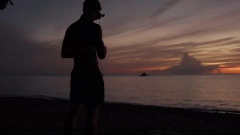 Silhouette of a man flying an fpv drone with goggles on at a beach on St. Lucia Stock-Footage 308722553