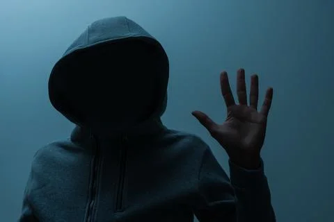 Silhouette of man in the hood or hooligan over dark background with copy space Stock Photos