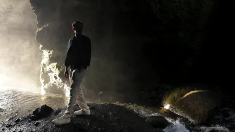 Silhouette of man looking back in a cave, Seljalandsfoss waterfall, Iceland Stock Footage 254117273