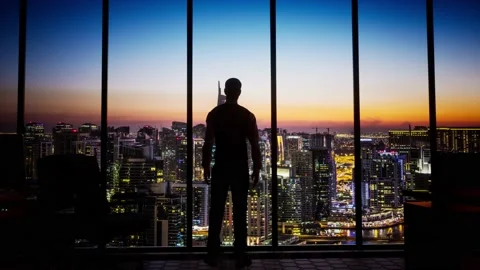 A Silhouette man looking out office window at dubai skyline Stock Footage 155222695