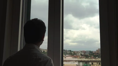 Silhouette of a man looking out the window. View of the sky and the city Stock Footage 129437737