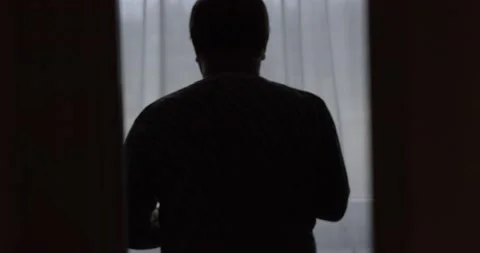 Silhouette of a man looking out the window Stock Footage