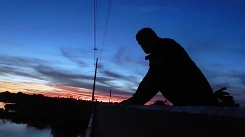 Silhouette of man looking over bridge to sunset Video stock 45290139