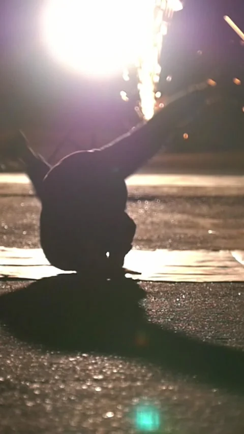 Silhouette of man performing acrobatic elements through the sparks from grinder Stock Footage 346756536